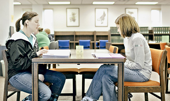 two students sitting at a table in the library