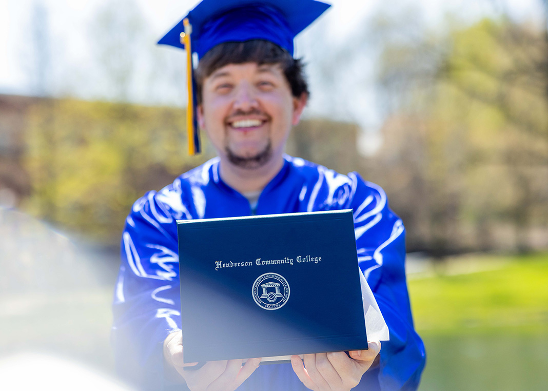student in graduation attire holding diploma