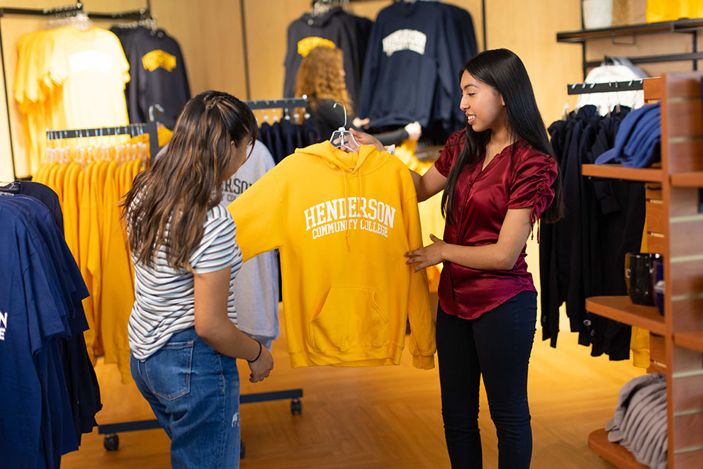 two HCC students looking at an HCC shirt in the bookstore