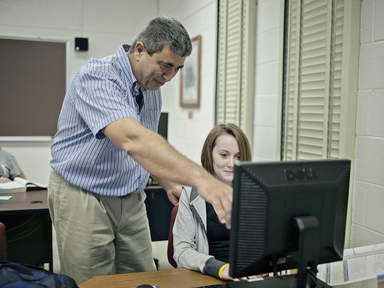 Instructor helping a student with a computer. 