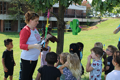 a woman hanging a pinata surrounded by children