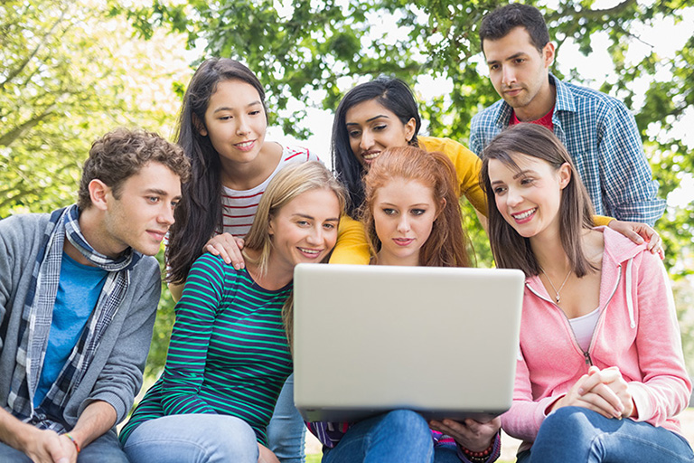 students outside gathered around a laptop