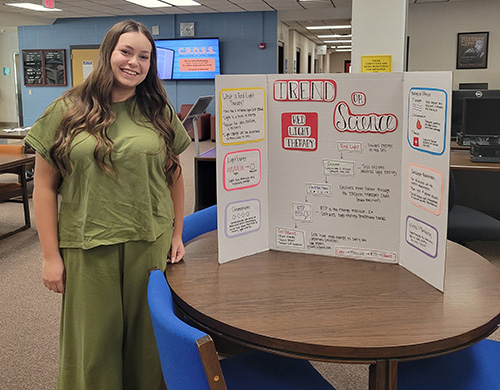 female student standing by a table display