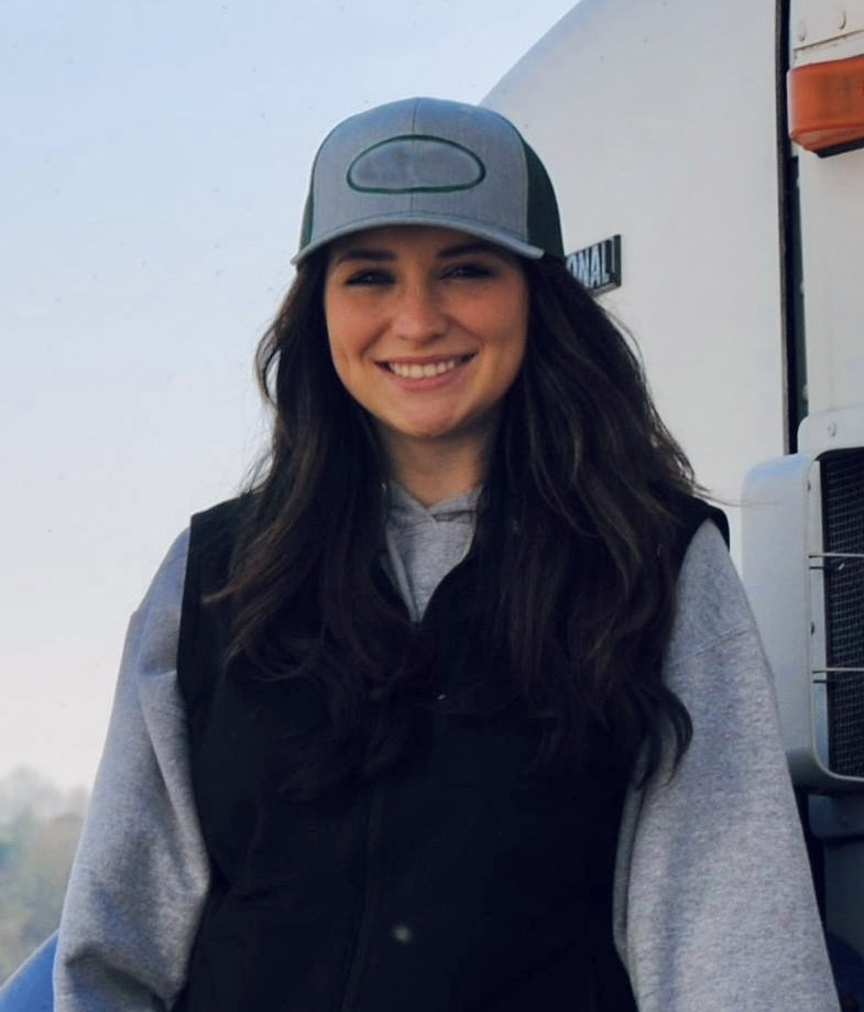 Girl standing outside next to a semi truck