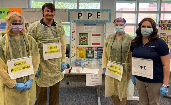students in PPE equipment in front of tables