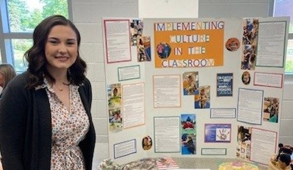 female student standing in front of a presentation board