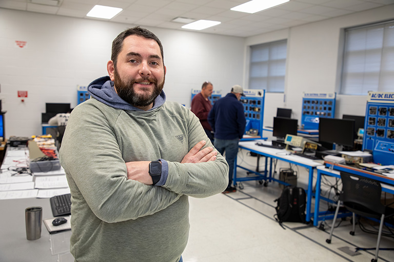 an industrial maintenance student standing in front of equipment and computers