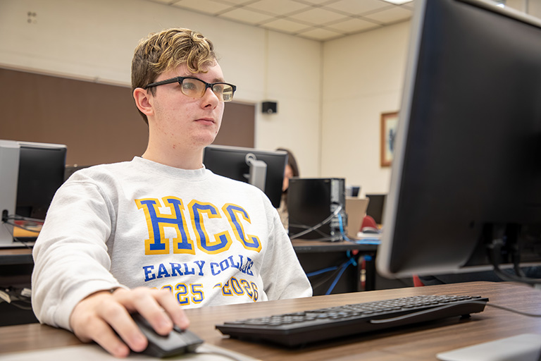a male student sitting at a computer