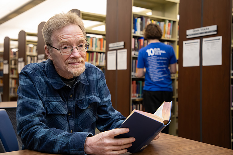 non traditional student reading a book in the library