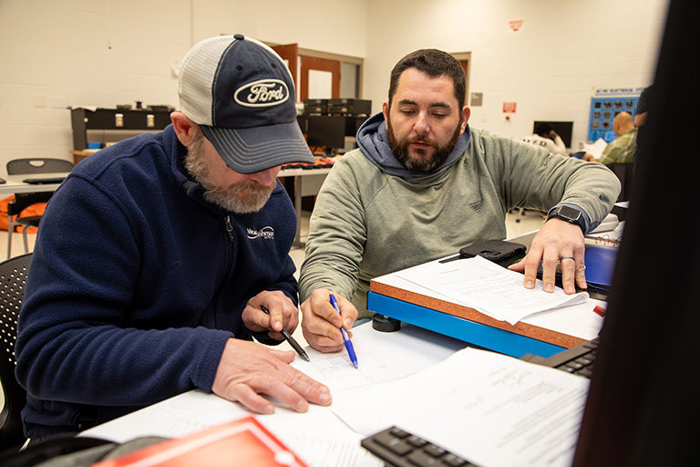two men sitting in front of electronic equipment