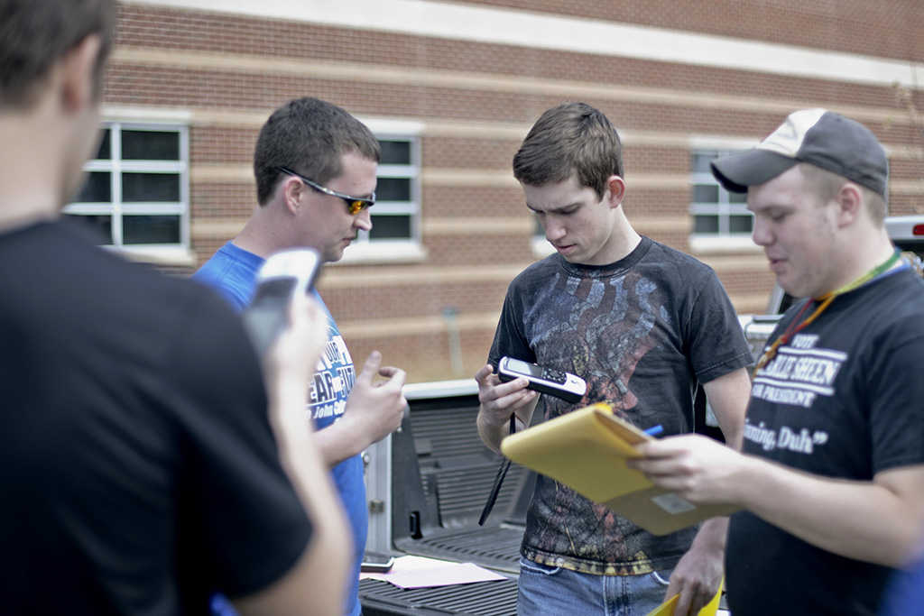 four students outside looking at equipment or taking notes