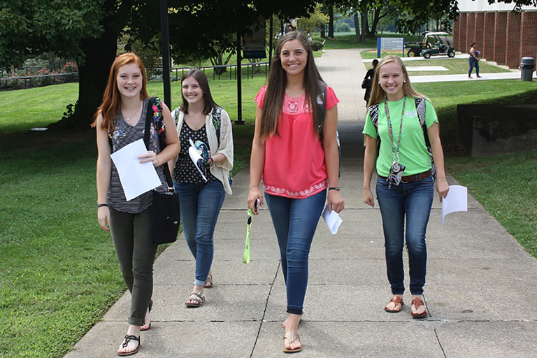 four girls walking on campus