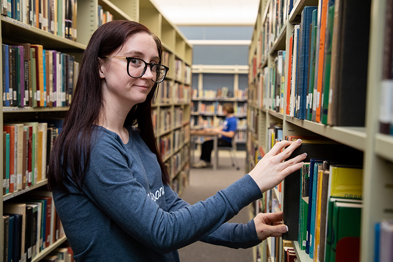 a student in a library looking at books