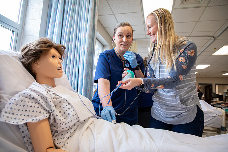 a nursing instructor and a student working on a patient manikan
